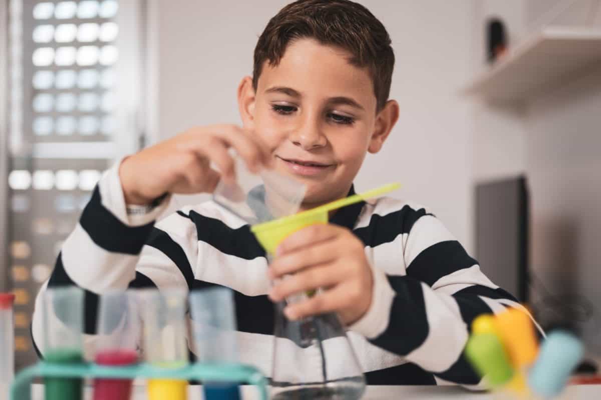 Little boy having fun with chemistry lab set. Science experiments at home for school projects homework.