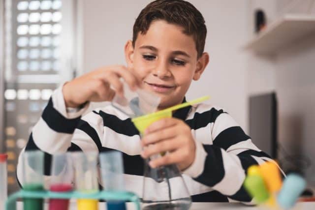 Little boy having fun with chemistry lab set. Science experiments at home for school projects homework.