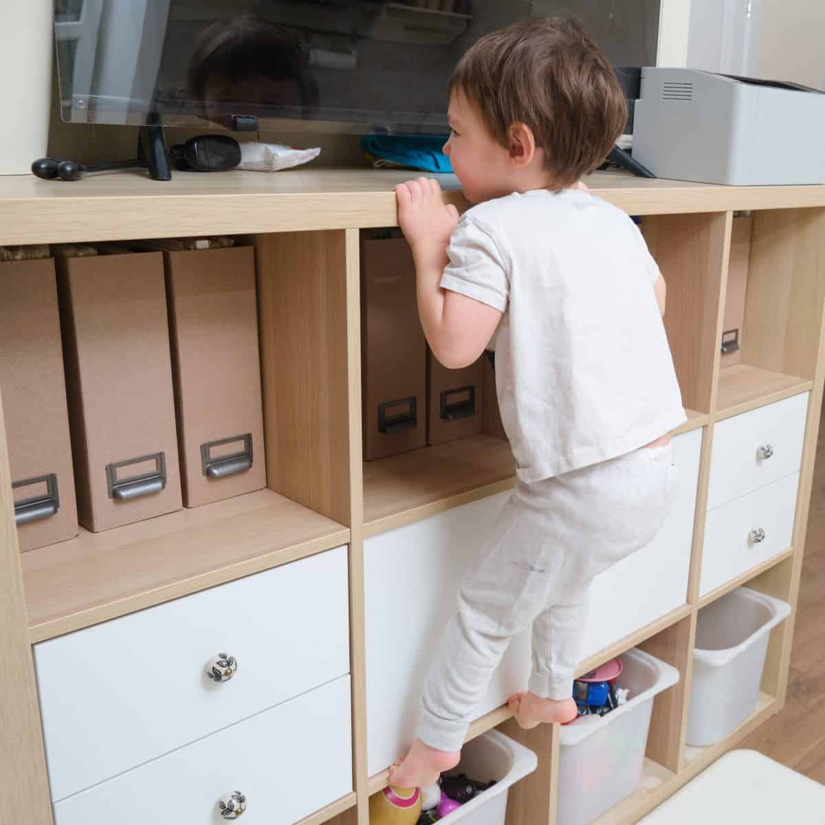 A child climbs on a closet, there are dangers in the house with the risk of injury. Kid aged two (two year old)