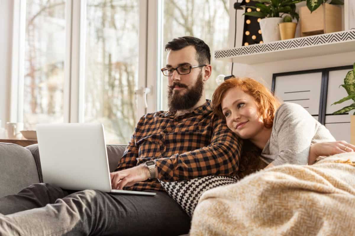 Smiling couple watching a movie on laptop. Happy wife and husband during date night