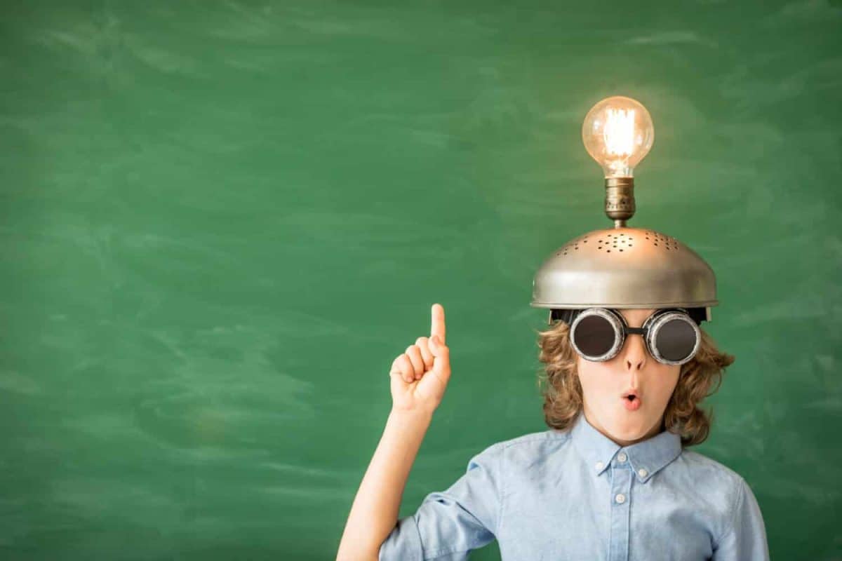 Portrait of child in classroom. Child with toy virtual reality headset in class. Success, idea and innovation technology concept. Back to school. Kid against blackboard with copy space