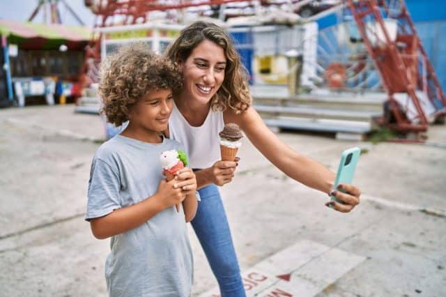 Mother and son eating ice cream make selfie by the smartphone at theme park