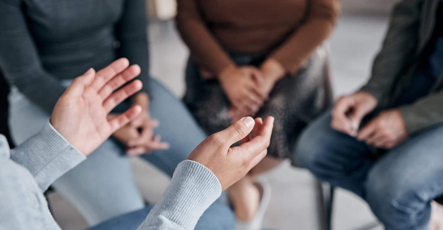 Support with group, therapy and mental health with hands and help, people together talking about problem and crisis. Psychology, healthcare and trust, respect and community in counseling for trauma