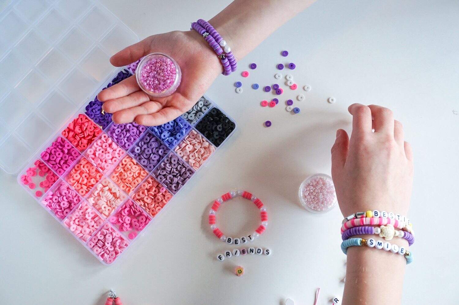 Jewelry making. Colorful beads and friendship bracelets. Two person. Only hands.