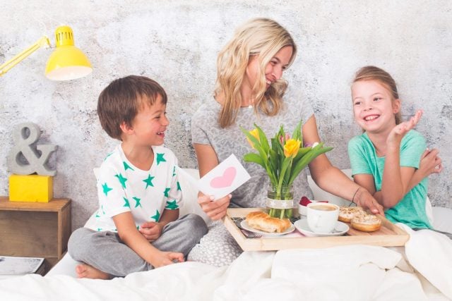 Mother´s Day - children surprise their mother with breakfast in modern bed
