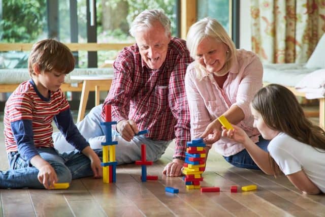 Grandparents are stacking building blocks together with their grandchildren at home