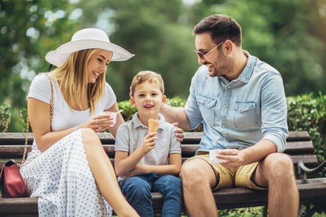 Young happy family spending their weekend in the park eating ice cream.