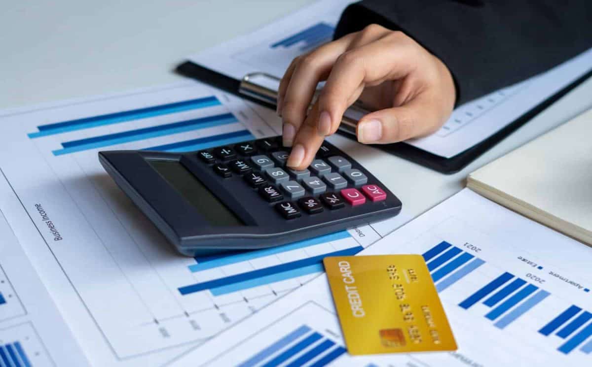 Businessmen use a calculator to calculate income and expenses in order to manage budgets to pay off credit card debt.