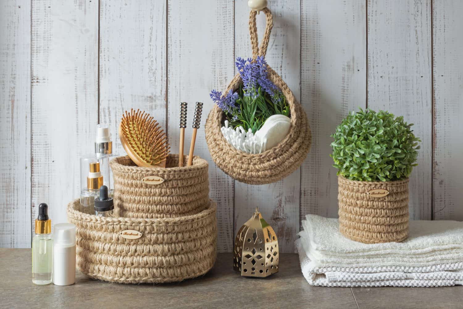 Hygienic accessories for bath and spa on the table in the bathroom. Wooden hairbrush, towel and green leaves. Eco containers for order in the bathroom