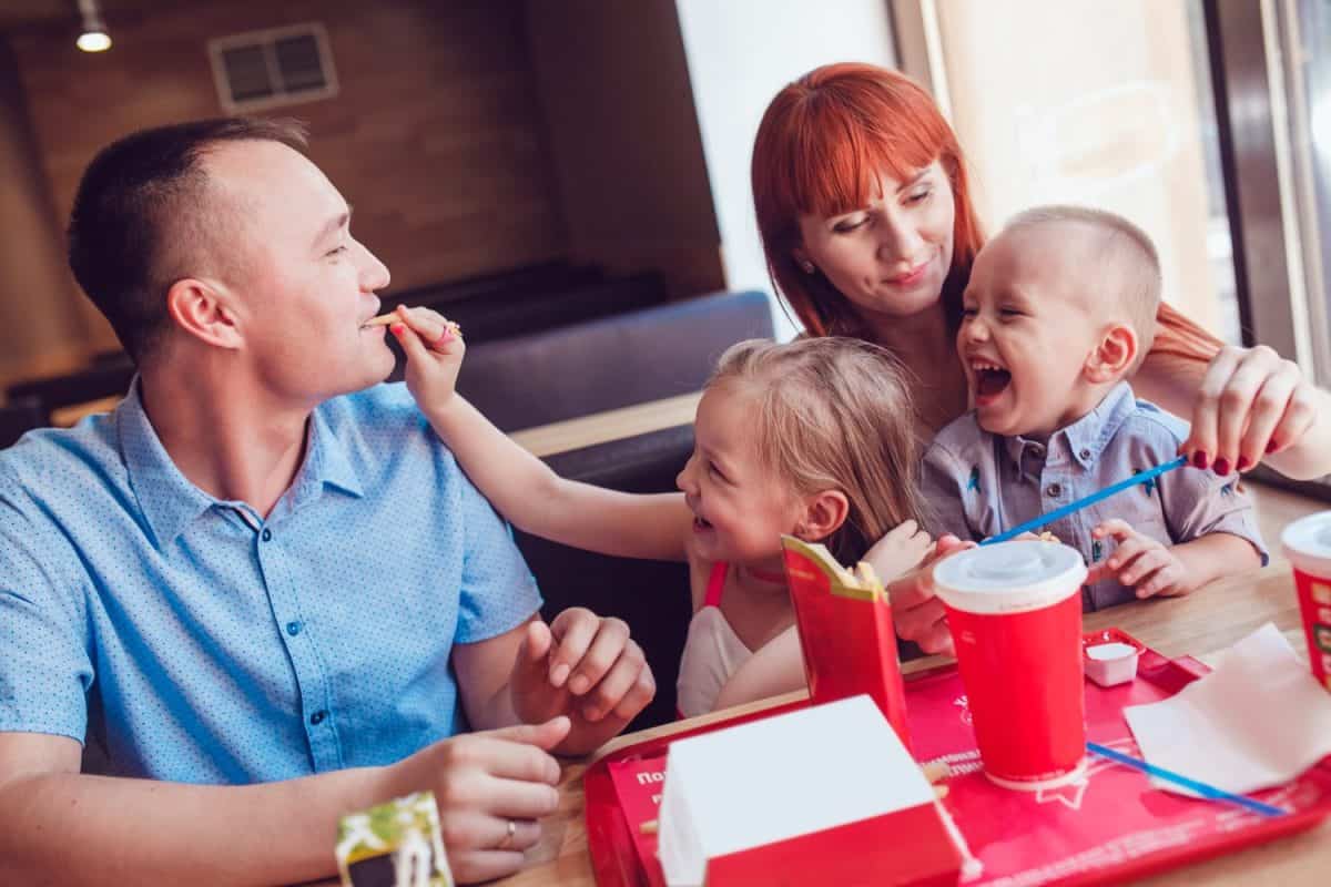 Happy family eating fast food in restaurant all together