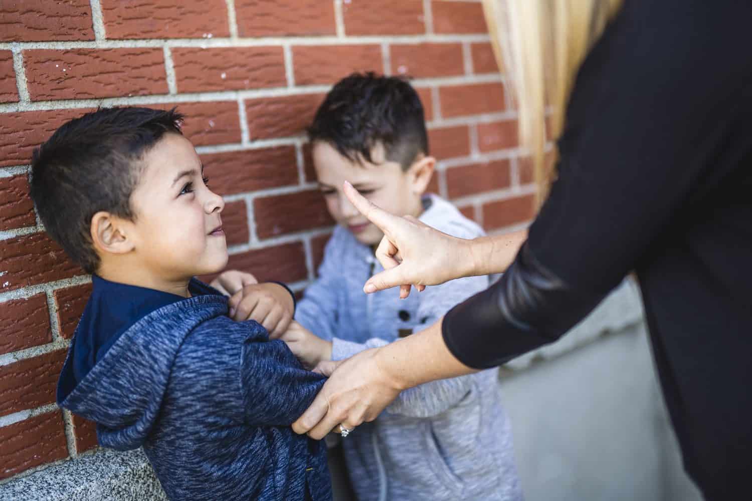 A Teacher Stopping Two Boys Fighting In Playground