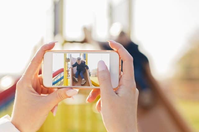 Mother taking photo of her child on playground
