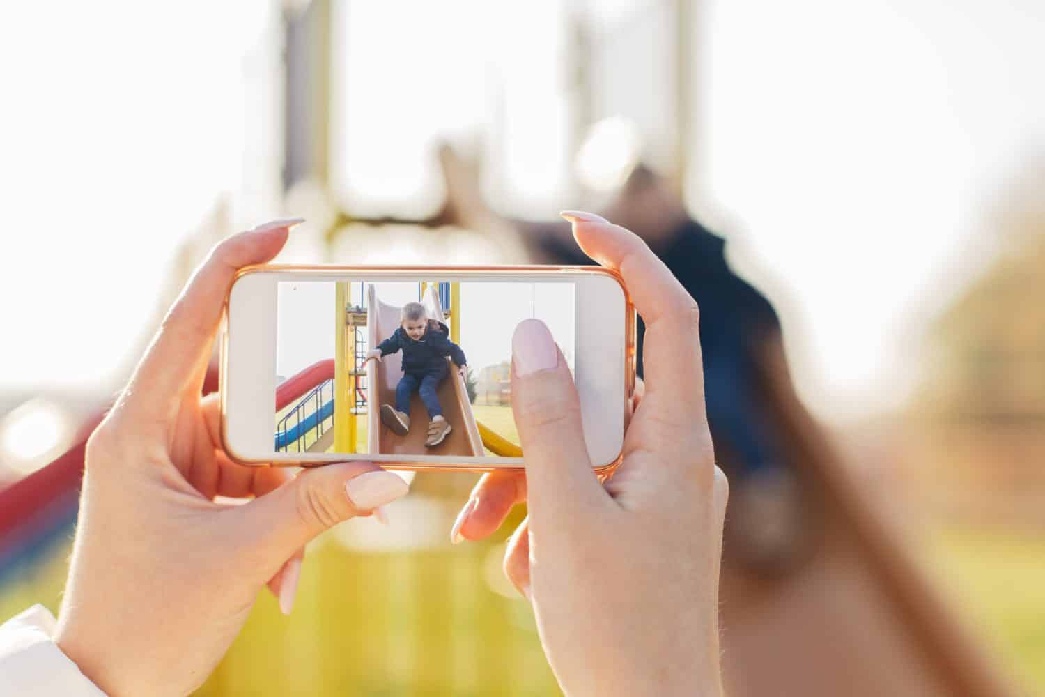 Mother taking photo of her child on playground