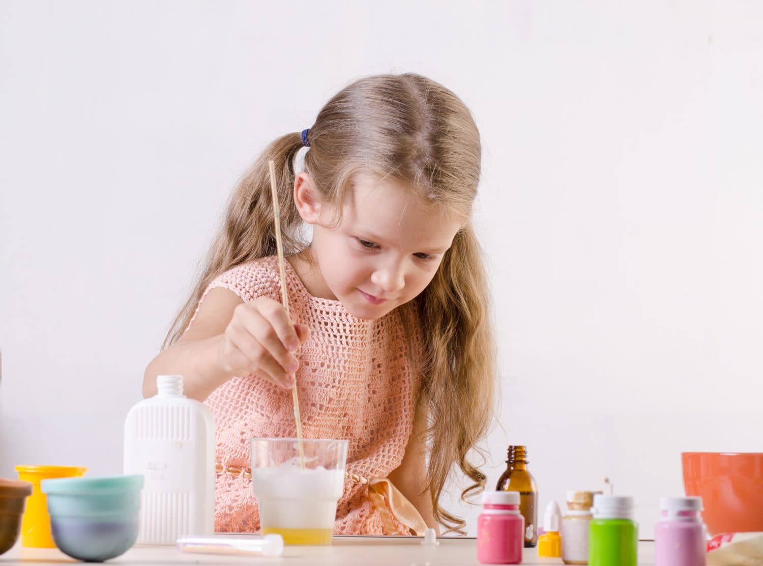 Adorable little girl making slime toy, meshes ingredients for worldwide popular self made toy. Slime making process.
