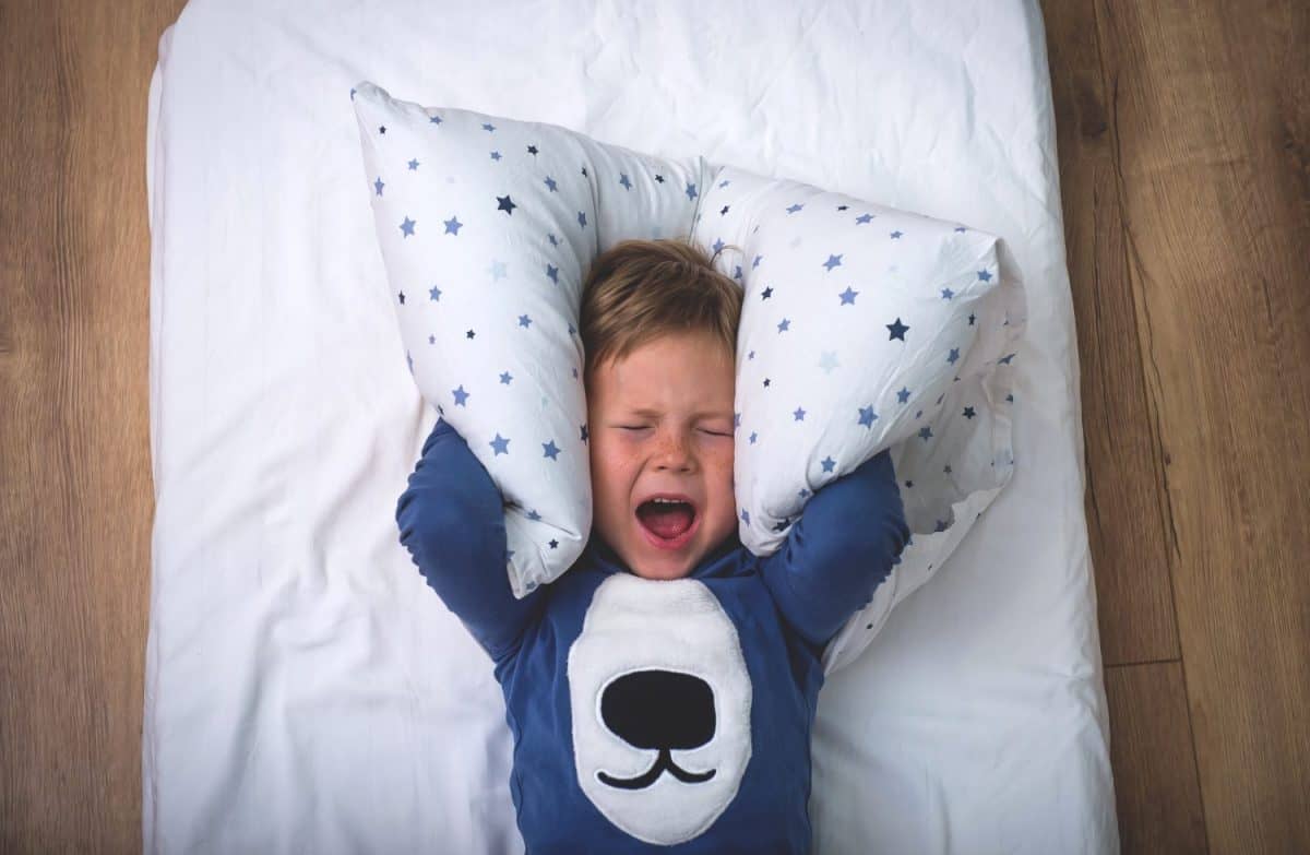 Child boy sleep with alarm clock. Time to get up and go to school. Stress