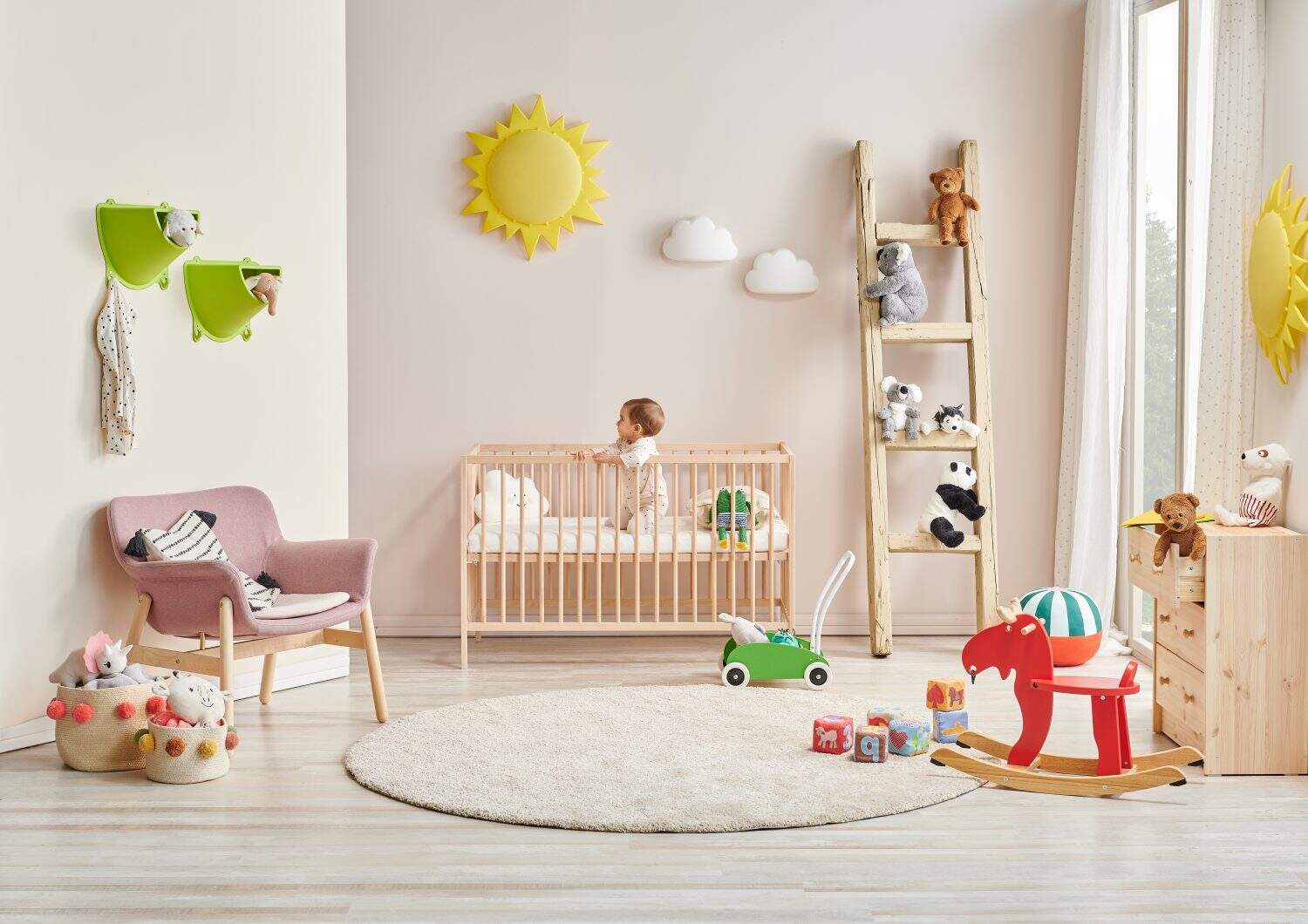 Modern baby room, wooden detail, cradle and crib, pink chair, cabinet, toy yellow sun. Baby in the bed.