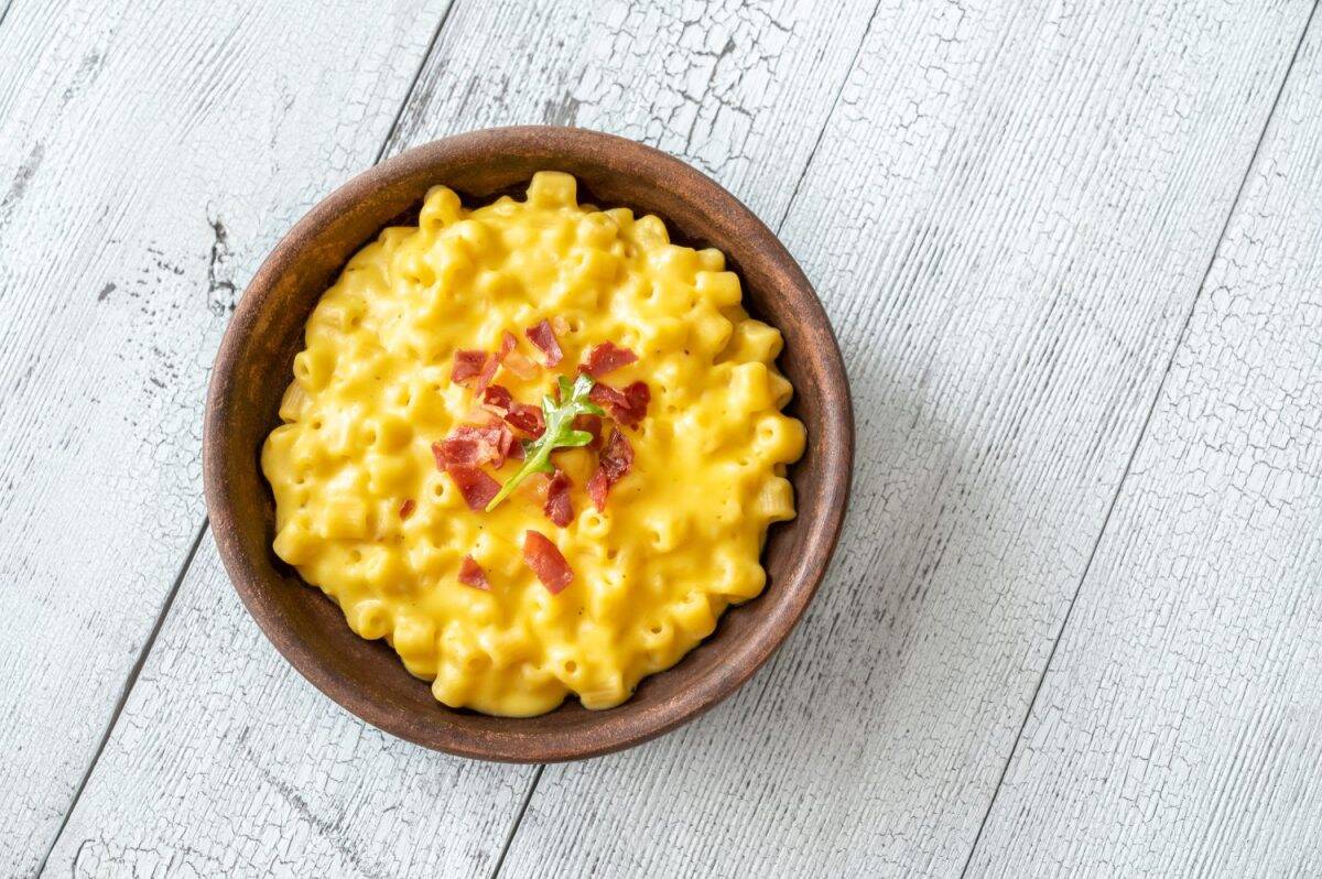 Bowl of macaroni and cheese with slices of fried bacon