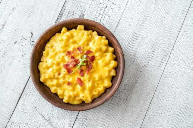 Bowl of macaroni and cheese with slices of fried bacon