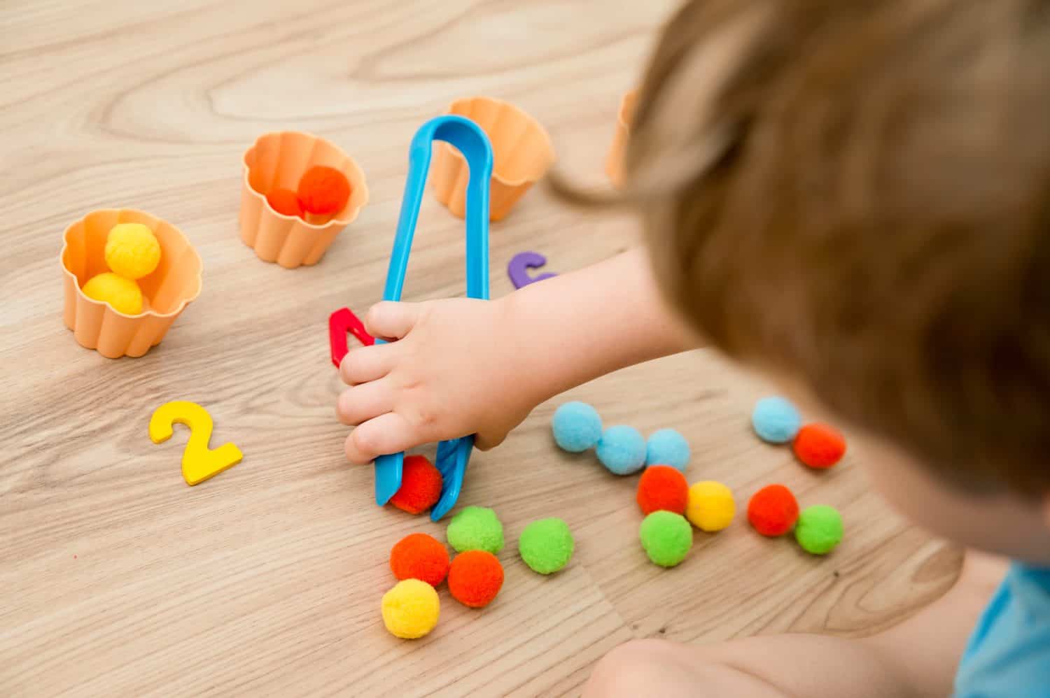 Put correct amount pom poms in silicone cake cup. 5 minute carfts. DIY children home activity. Early education, fine motoric skills. Elementary school mathematics