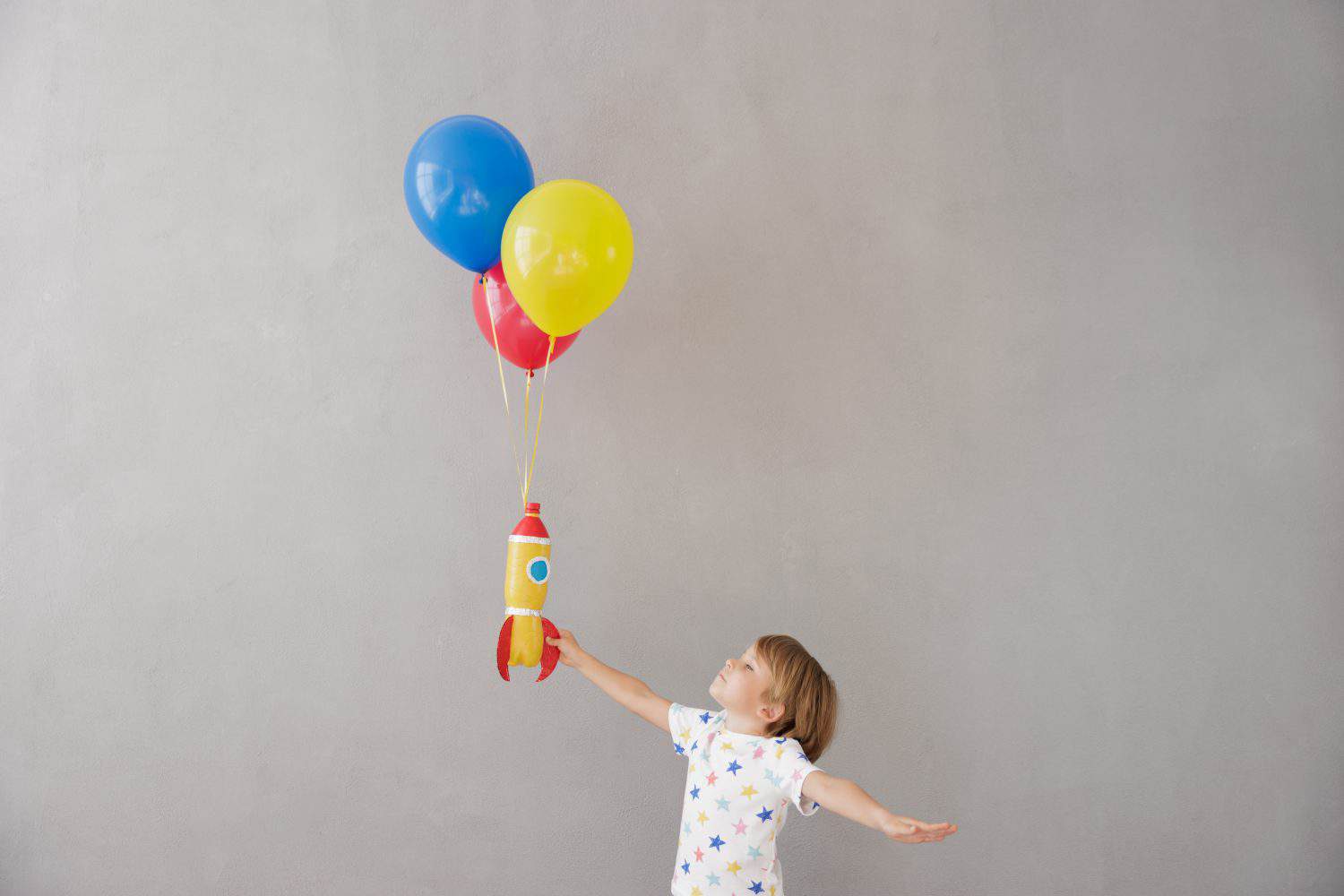 Happy child playing with toy rocket at home. Kid pretend to be astronaut. Imagination and children dream concept
