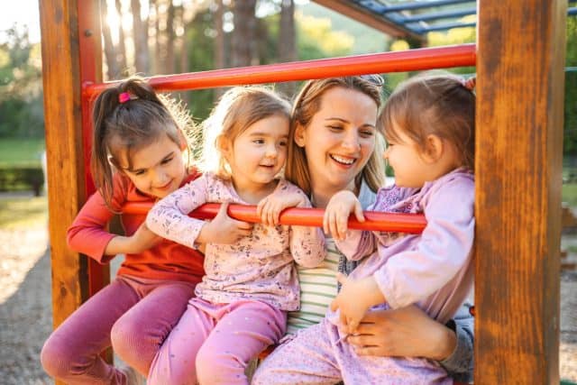 Smiling mom with daughters on the playground