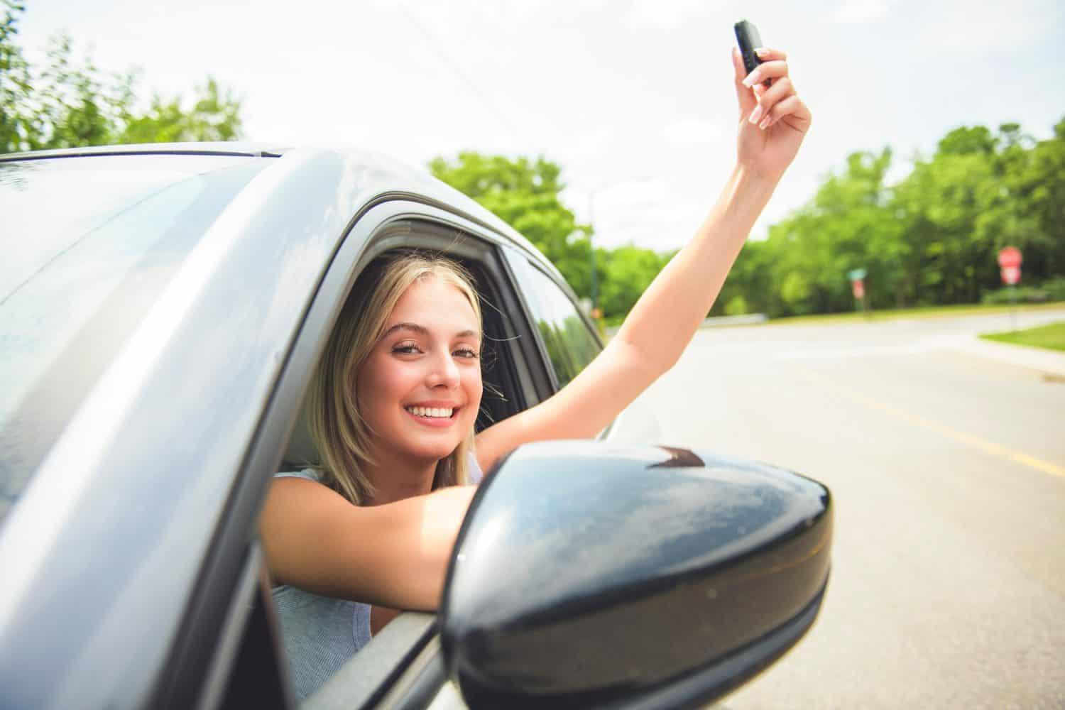 A Happy teen girl driver on car on summer day