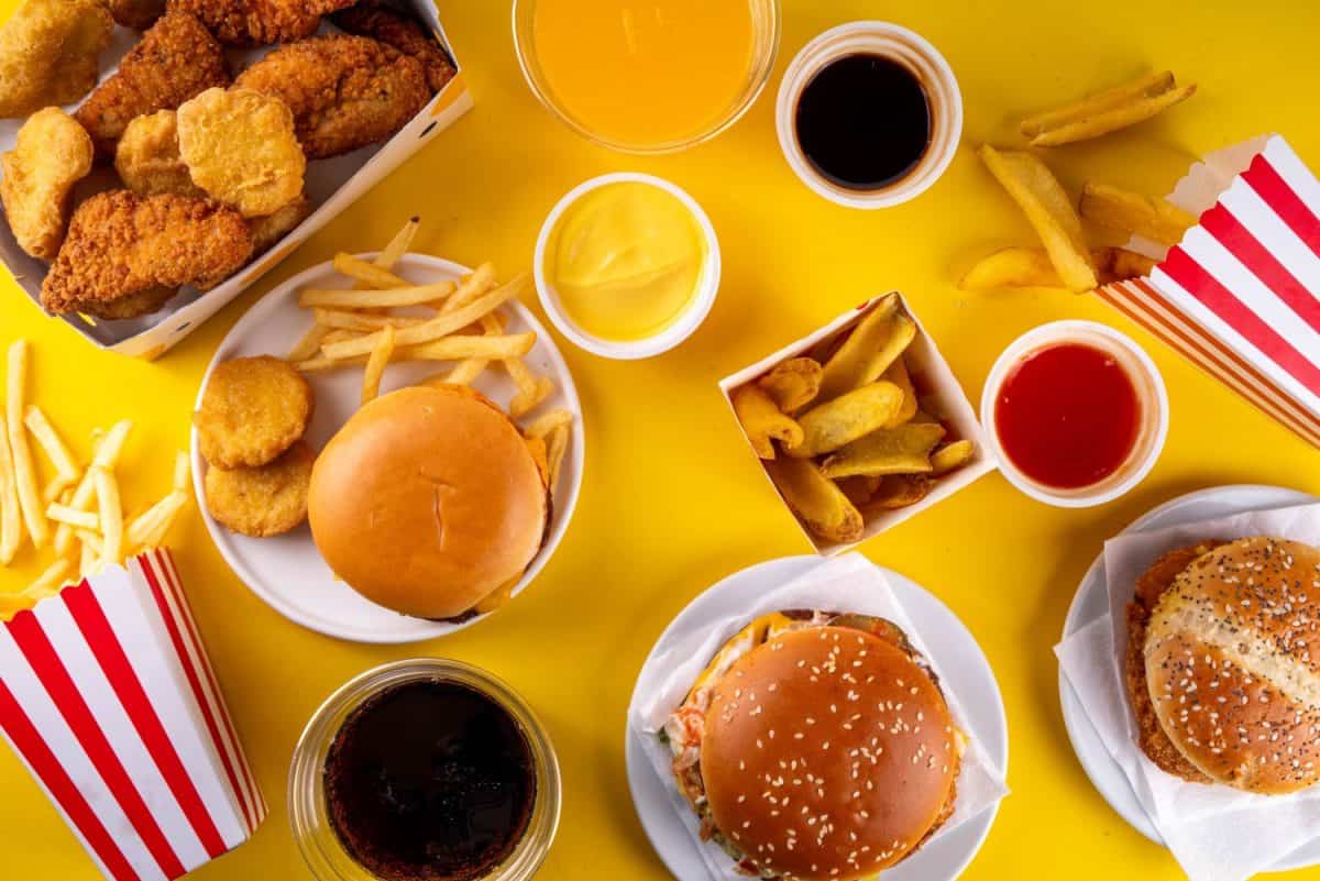 Fast food delivery menu background with various burgers, cheeseburger, nuggets, french fries, fizzy soda drinks. Junk unhealthy fast food, Ultra processed food with low nutrition, high calories value