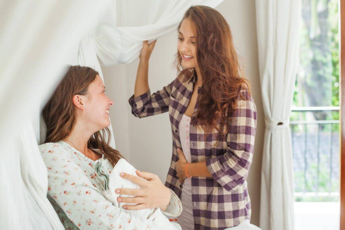sister visiting a young mother with her newborn infant in clinic