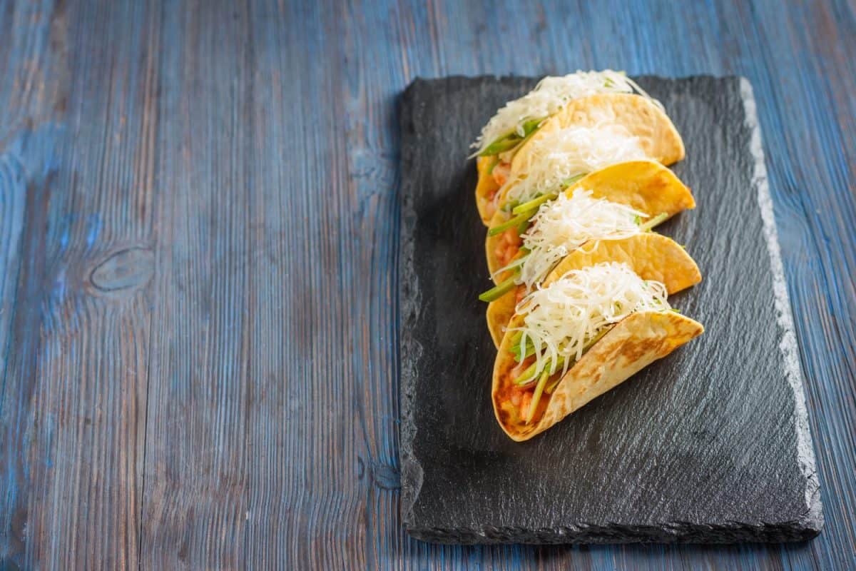 Mexican tacos with meat, beans, avocado, cheese and tomato sauce