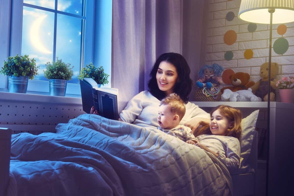 Family reading bedtime. Pretty young mother reading a book to her daughters.