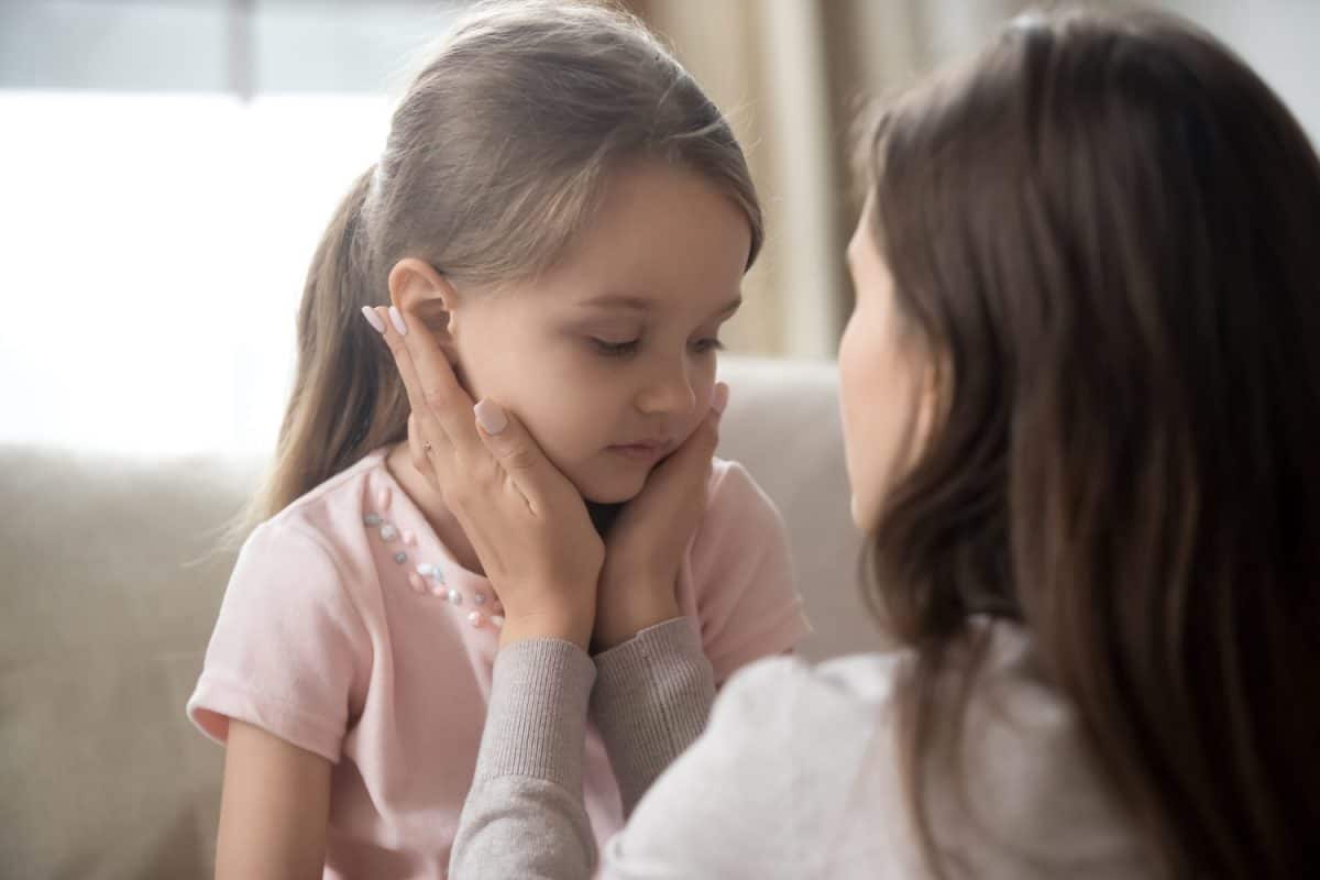 Loving young mother touching upset little daughter face, expressing support, young mum comforting offended adorable preschool girl, showing love and care, child psychologist concept, close up