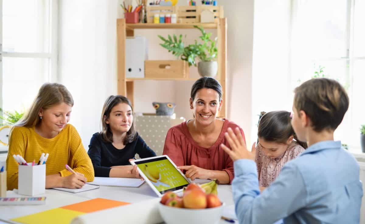 Group of homeschooling children with teacher studying indoors, coronavirus concept.