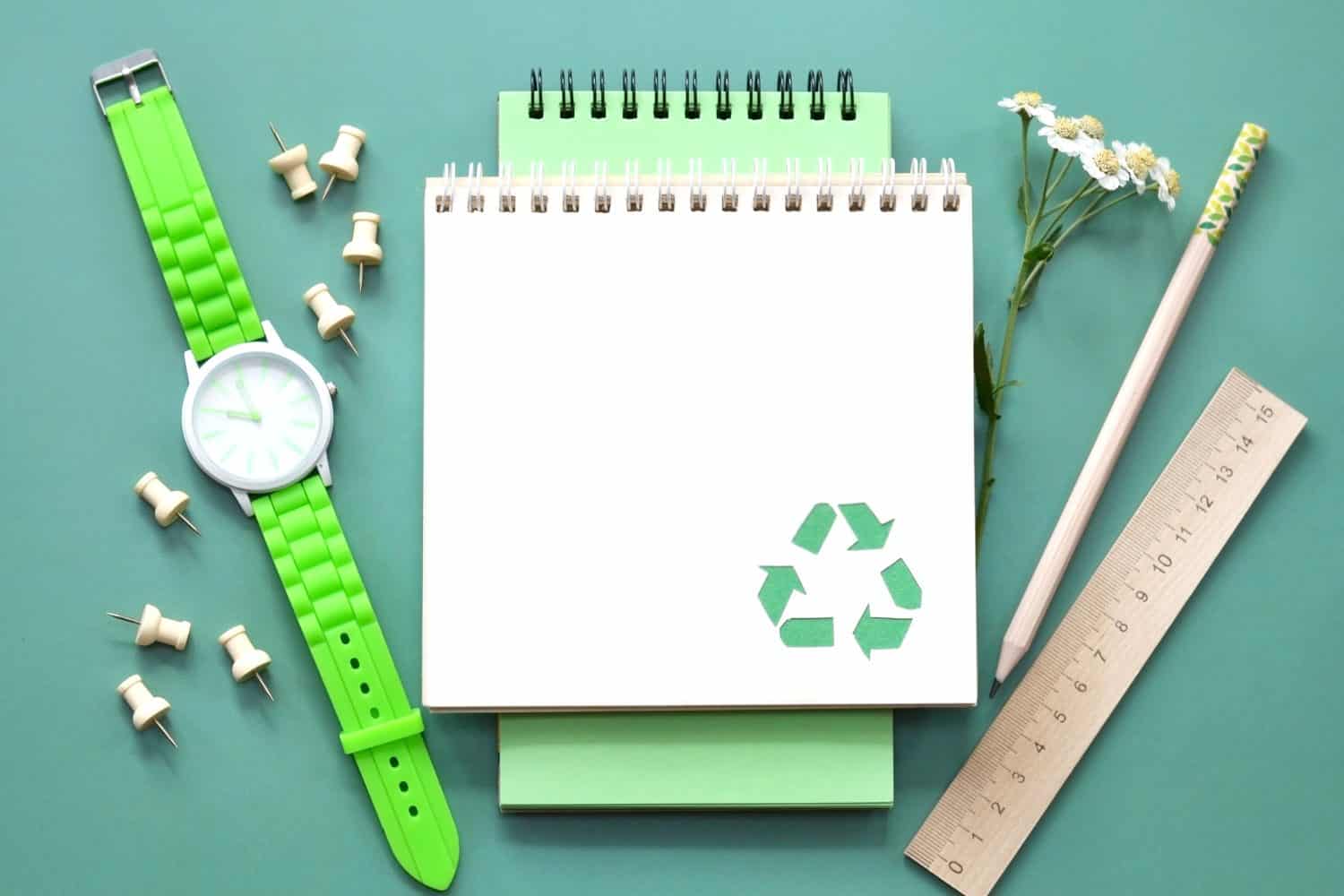 Eco friendly notebook with recycle symbol, wooden pencil, ruler, pushpin, green watch. copy space. Office eco friendly. back to school. think green. recycle