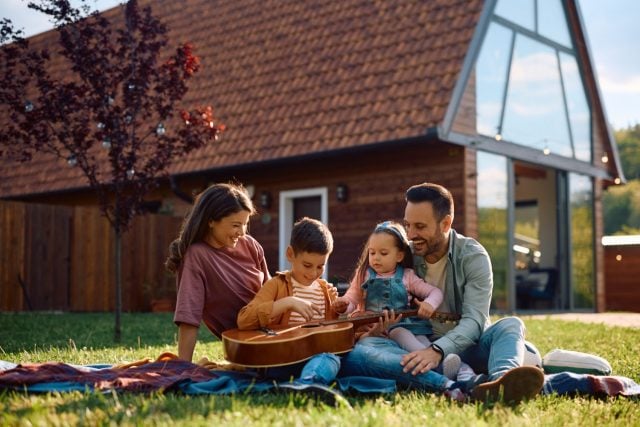 Little boy playing acoustic guitar during family camping. Copy space.