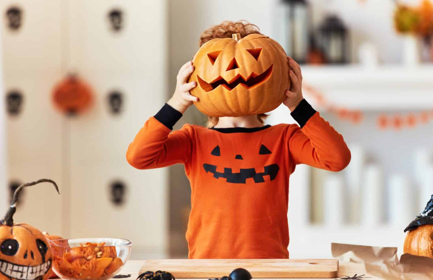 anonymous funny ginger boy in a costume with a pumpkin  Jack o lantern for a head during a Halloween celebration