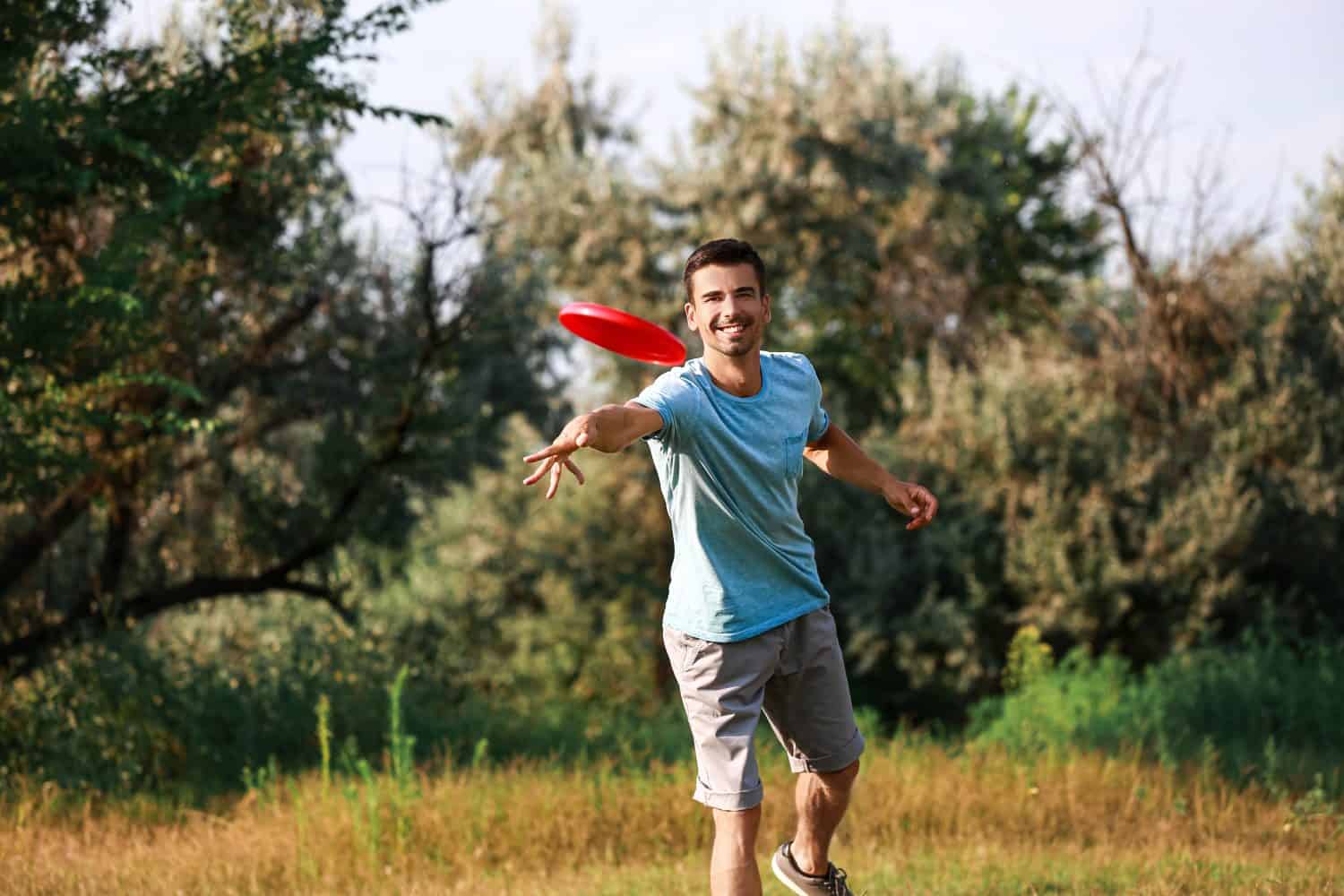 Young man throwing frisbee in park