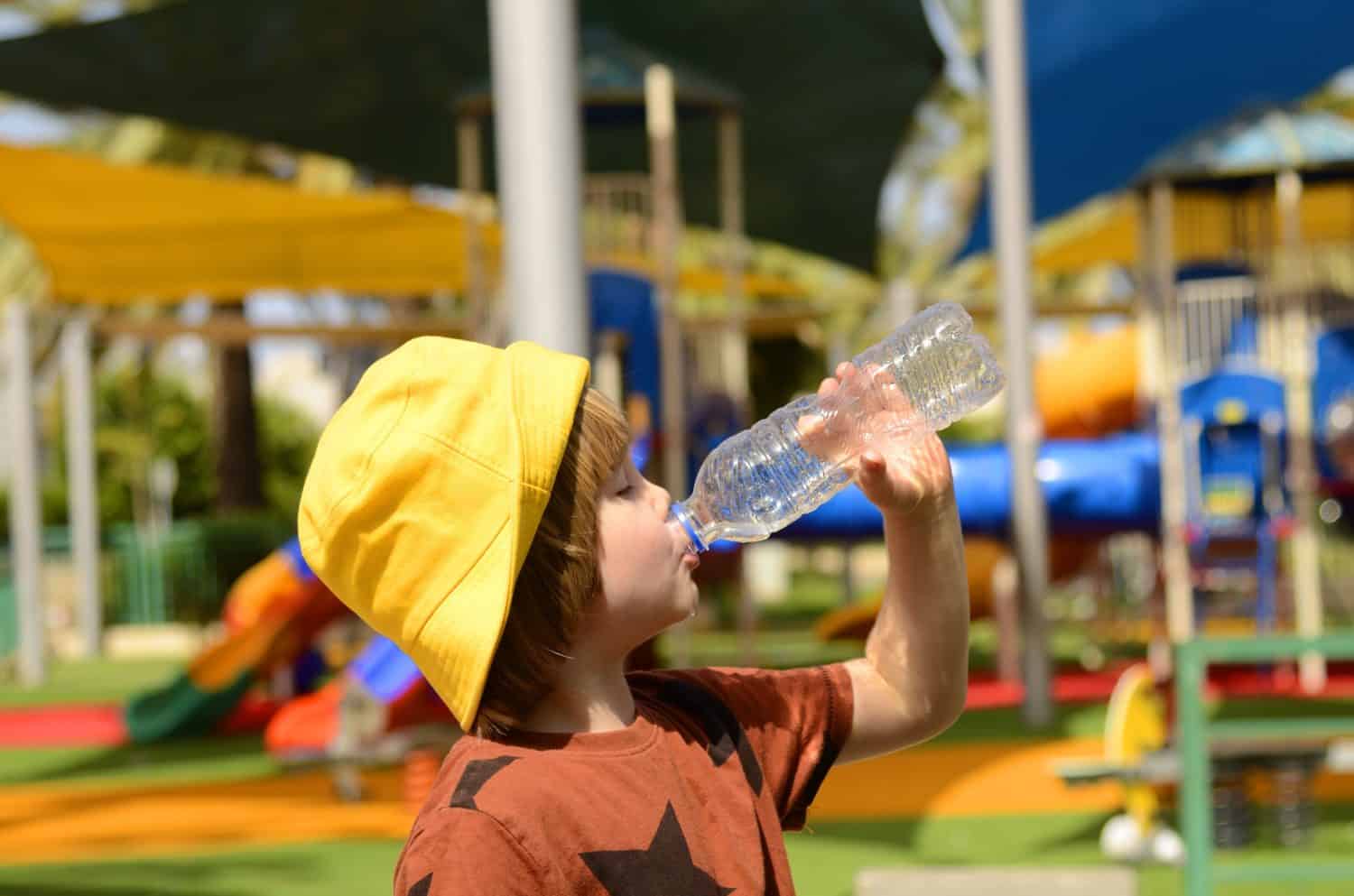A cute boy drinks water from plastic bottle. Summer thirst, preschooler drinking water on a hot day