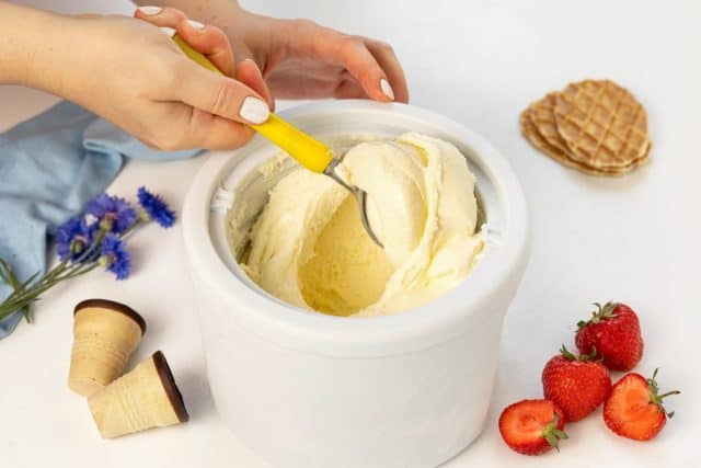 Homemade vanilla ice cream in ice cream maker on white table
