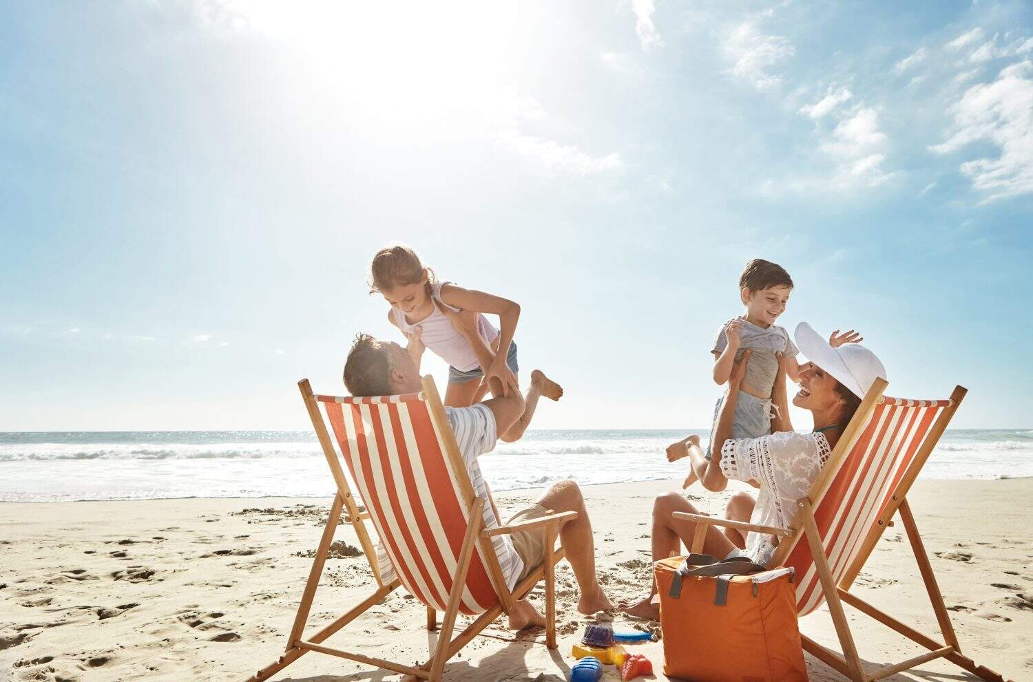 Family, beach and kids relax chair vacation adventure, bonding and play game together on tropical summer. Parents, children and excited of ocean island, energy and sunshine travel in Greece