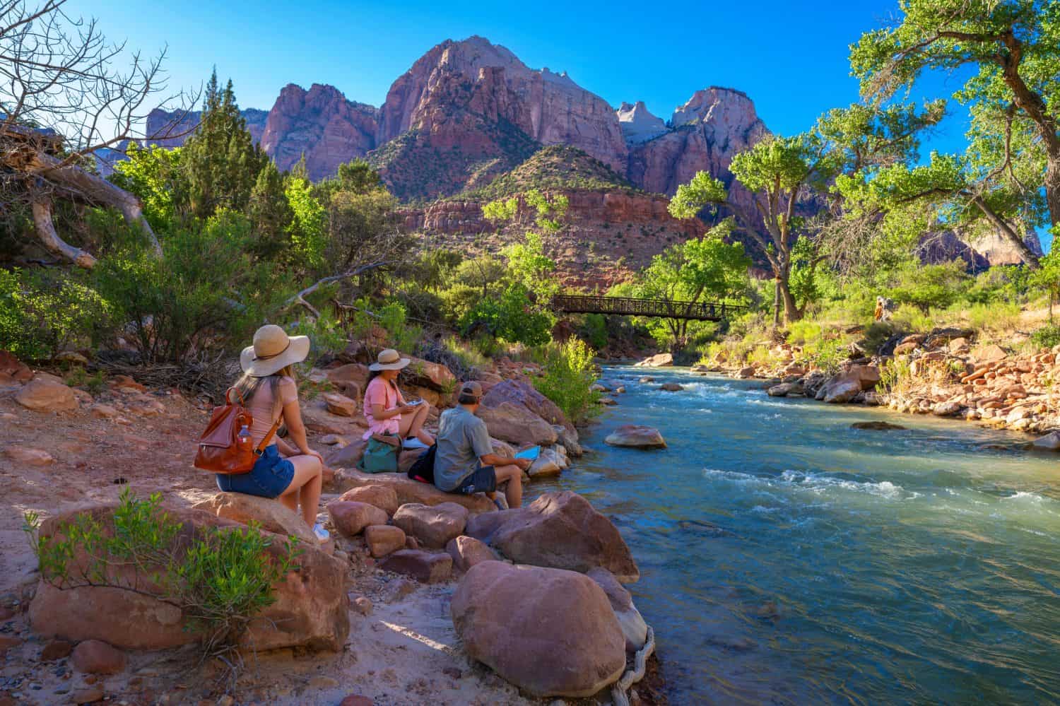 Family relaxing by the river on hiking trip in Utah. Family sitting by the Virgin River. Pa'rus Trail. Zion National Park, Springdale , Utah, USA.