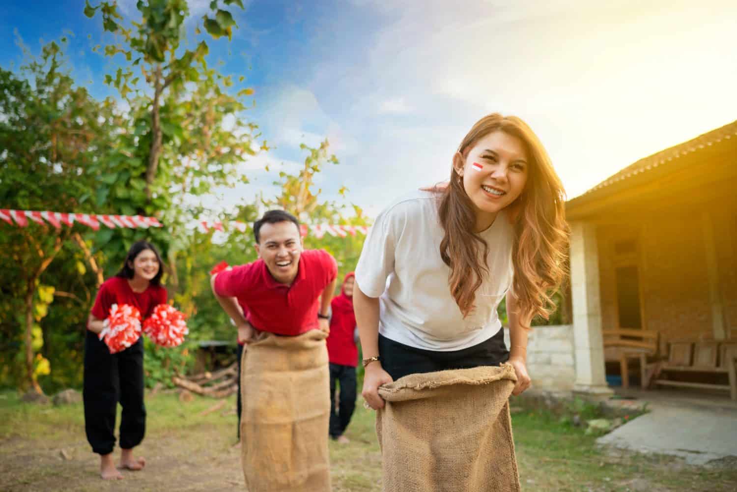 A group of people are playing a game of sack race. Scene is lighthearted and fun, as the group of people are laughing and enjoying themselves. Indonesian independence day concept