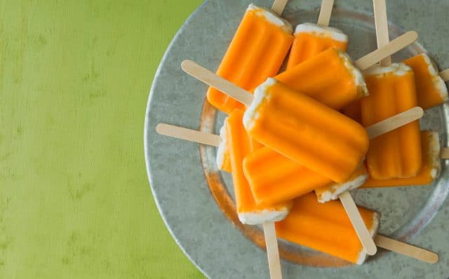 A bunch of orange creamsicle treats on a galvanized steel tray. Over head shot.