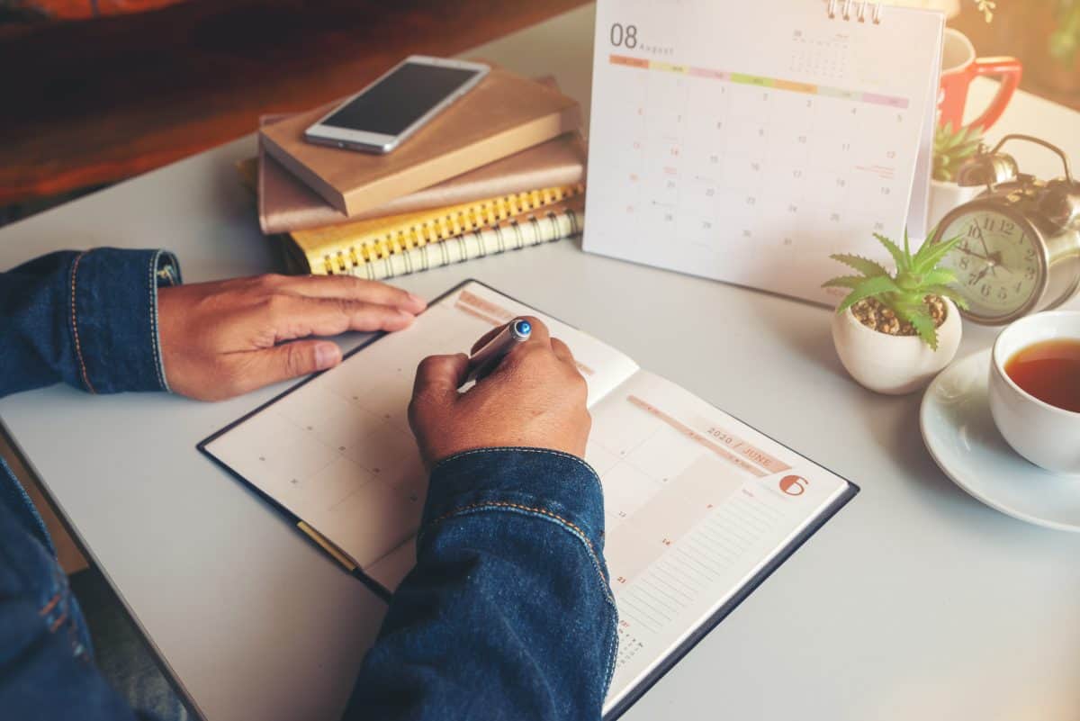 Male'hand of planner writing daily appointment On 2020 Calendar book.Asian man plan and noted schedule(holiday trip) on diary at office desk.Calendar reminder event for planner concept