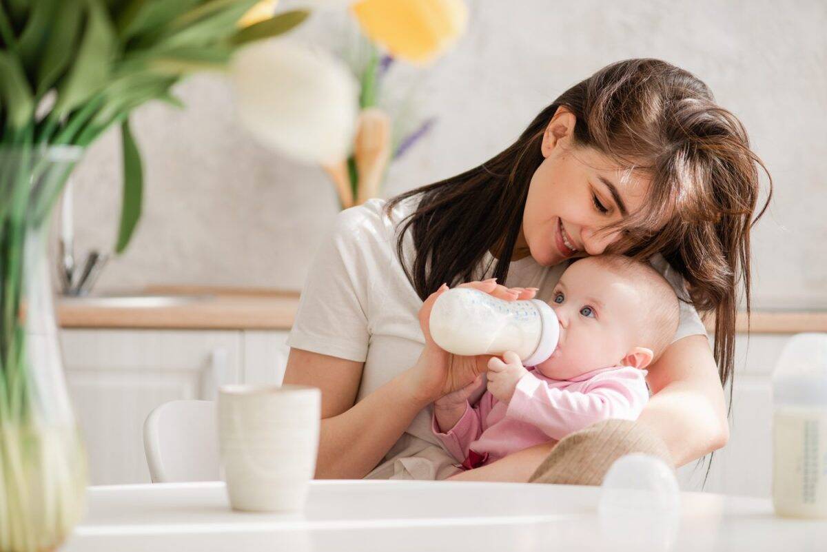 Feeding newborn girl with formula in a bottle.