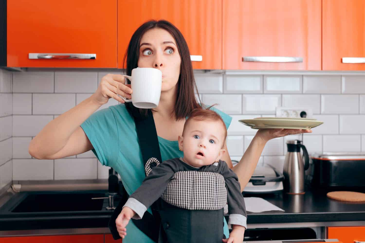 Busy Multitasking Mom with Baby, Coffee Mug and Dishes. Tired mother needing caffeine to do the household chores