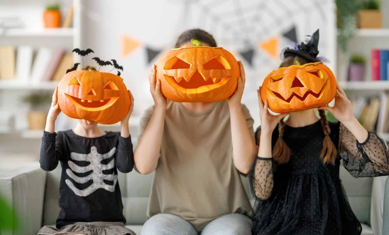Happy family preparing for Halloween. Mother and children in carnival costumes at home.