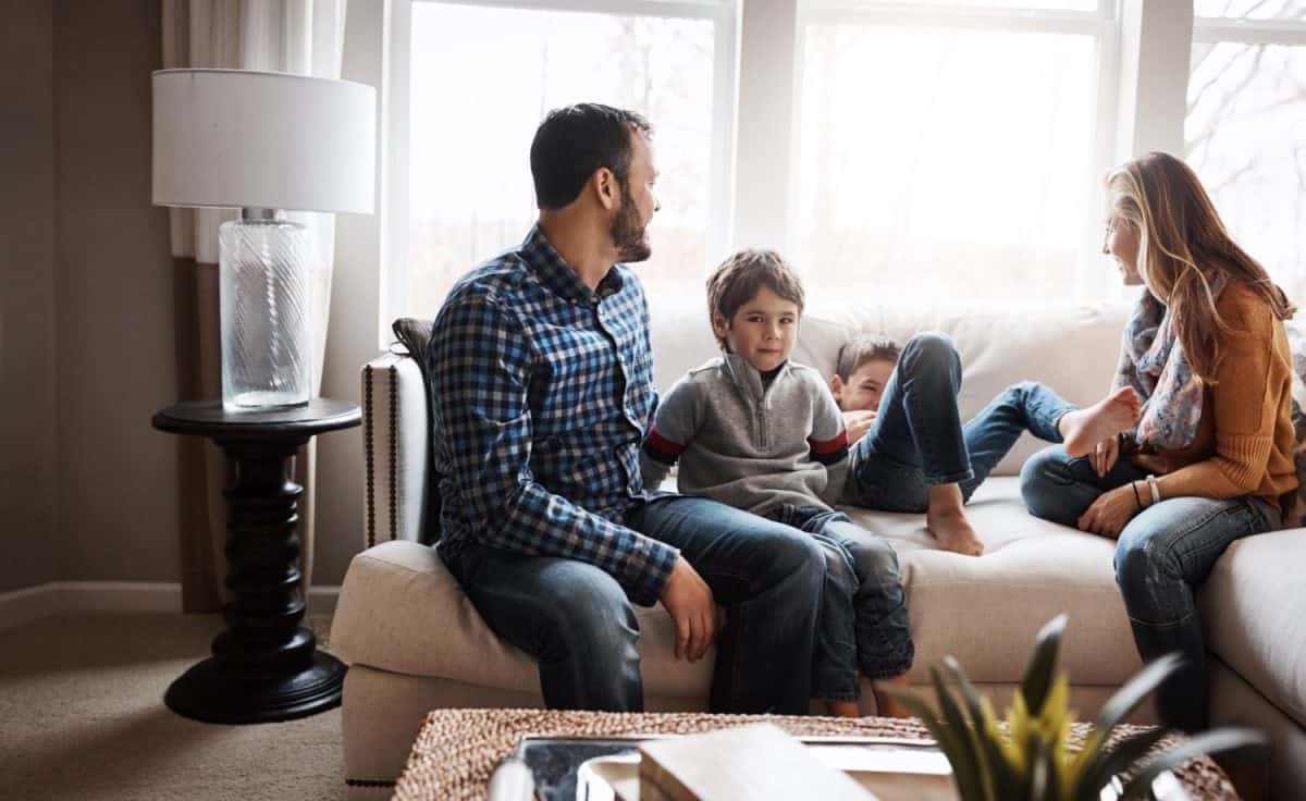 Parents, children and family with playing on couch, talking and bonding with love, holiday or memory in living room. Mother, father and kids with games, care or connection to relax with smile in home