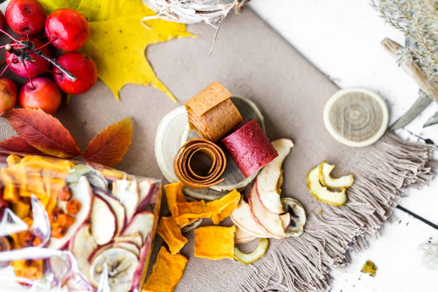 Freshly rolled, homemade fruit leather and dried fruit slices made from organic ingredients are displayed on a rustic table