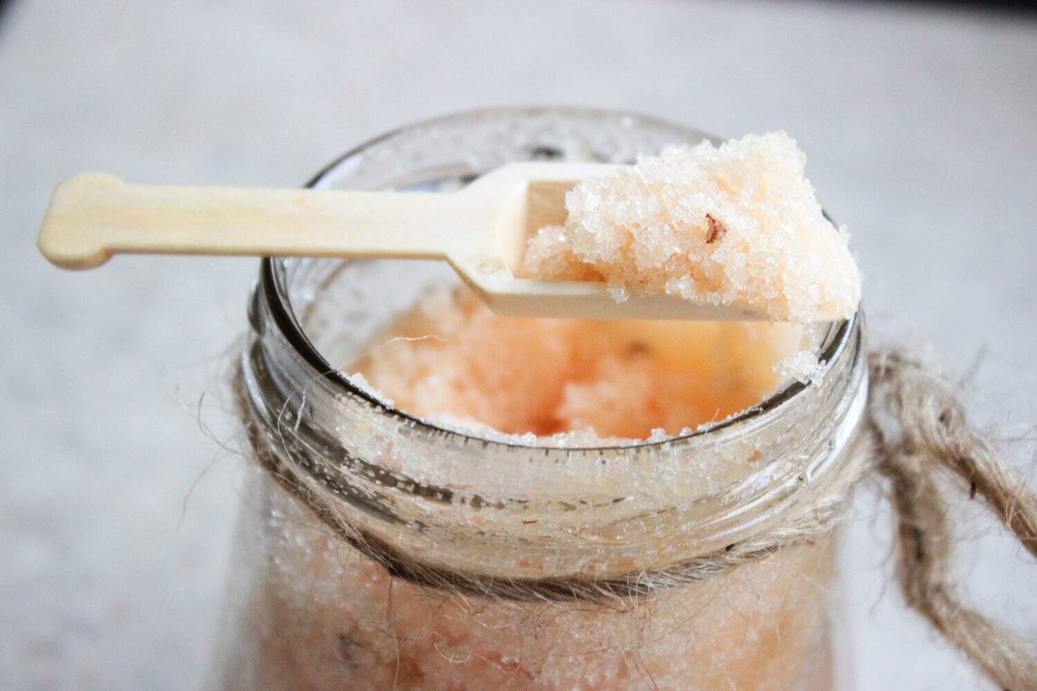 Bath salt with wooden scoop on open glass mason jar