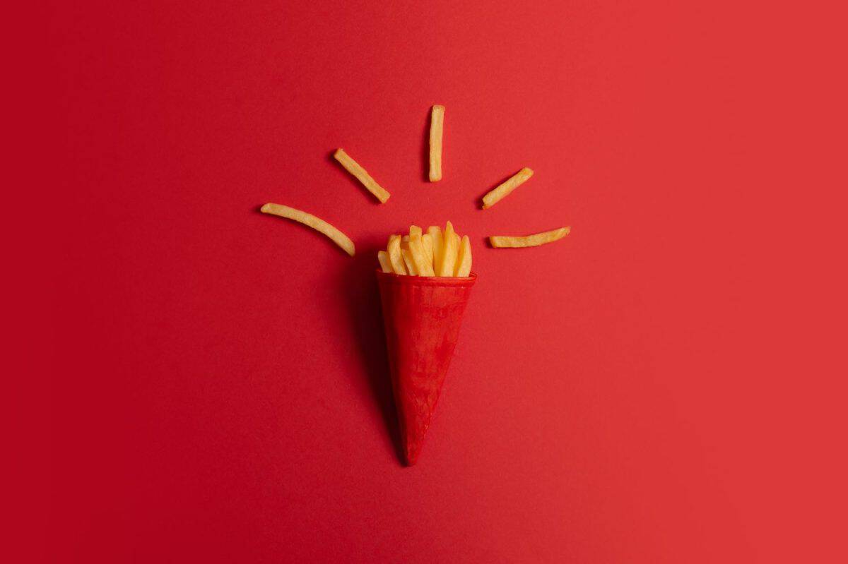 McDonald's menu: French fries in a cup on a red background. Minimal concept